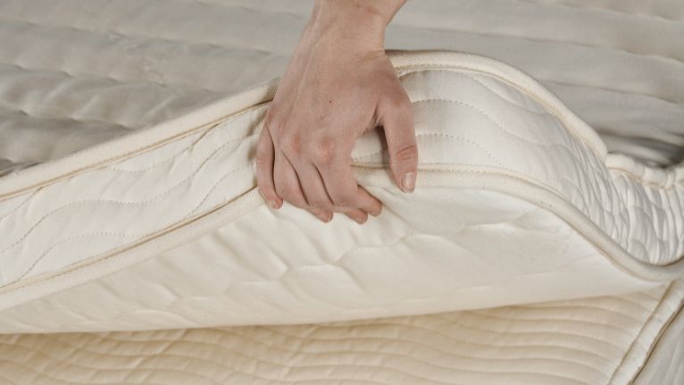 Hand lifting a mattress topper layer