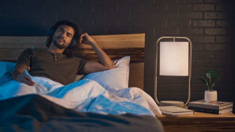 Man relaxing in bed with headphones