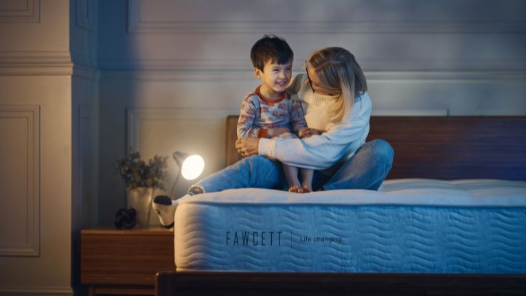 Mother and child smiling while sitting on a Fawcett mattress
