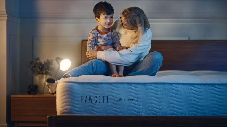 Mother and young son sitting playfully on a bed
