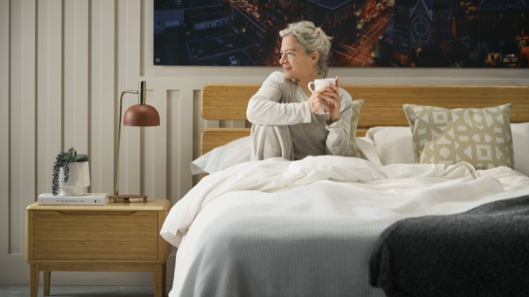 Old Woman Sitting on a Bed While Holding a Cup