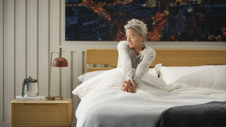 Older woman stretching in cozy bed