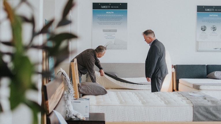 Two men inspecting a mattress in a Fawcett showroom